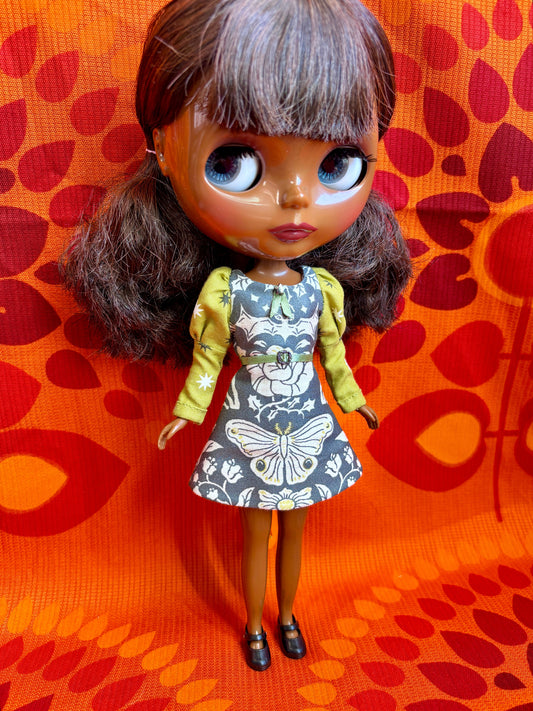 Doll wearing a floral dress on an orange patterned background