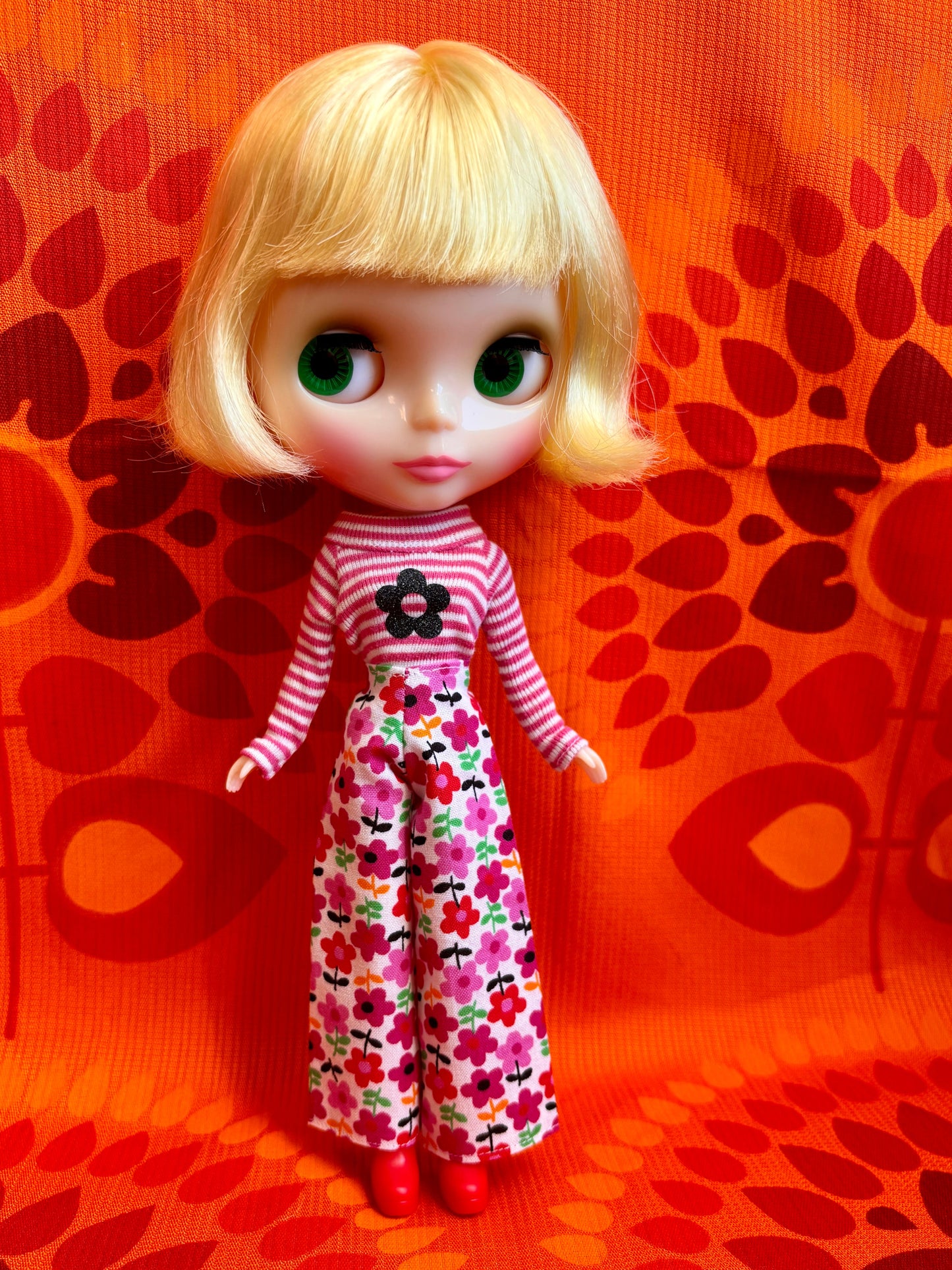 Doll with a striped shirt and floral pants on an orange background