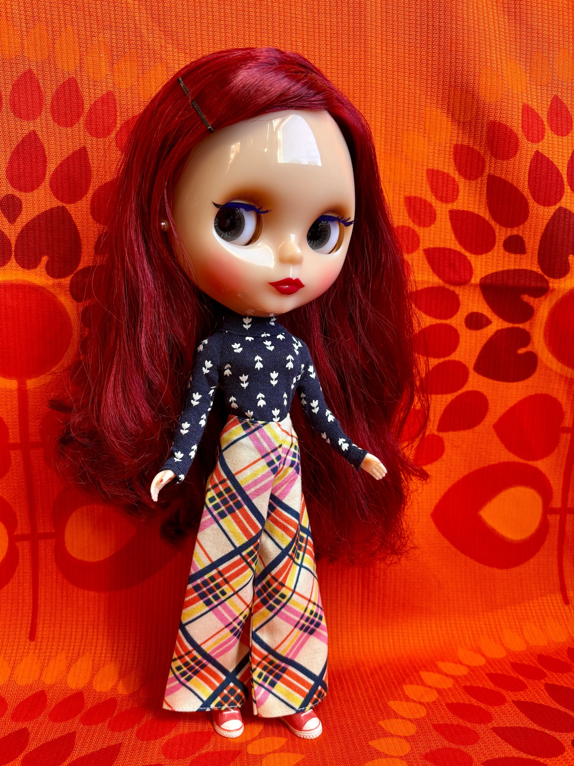 Doll with red hair and a patterned outfit on an orange background
