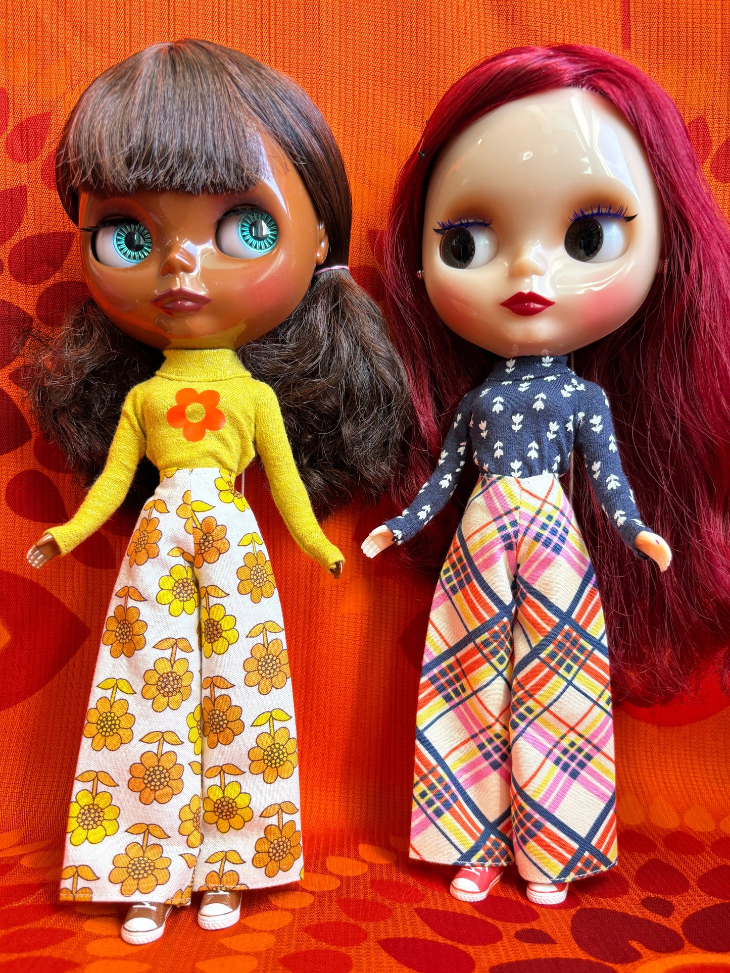 Two dolls with colorful outfits on an orange patterned surface