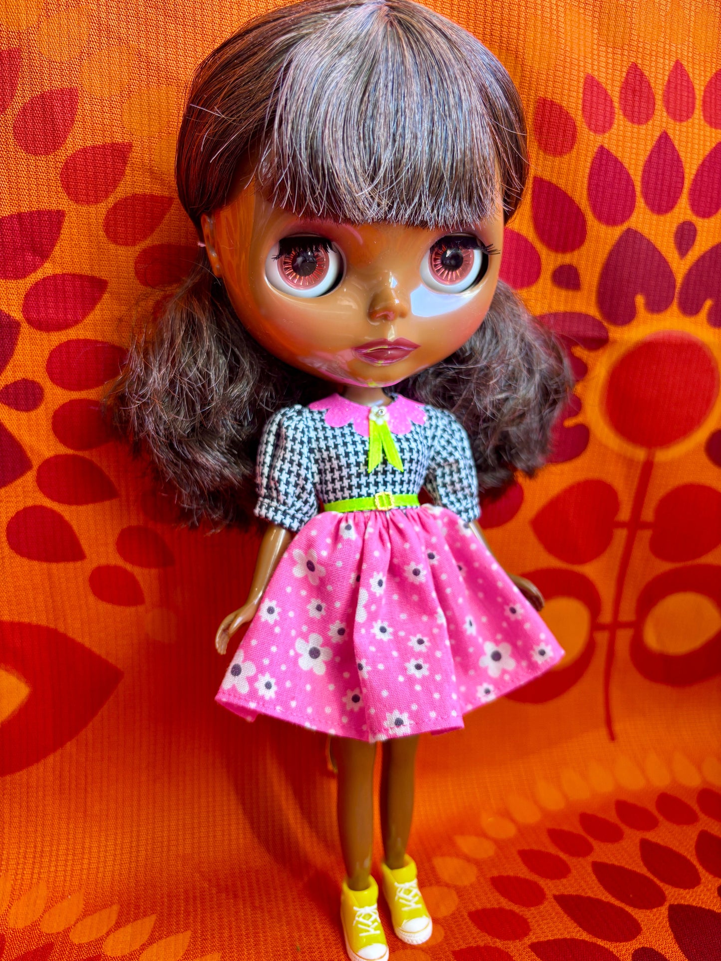 Doll with a pink dress and yellow shoes on an orange background