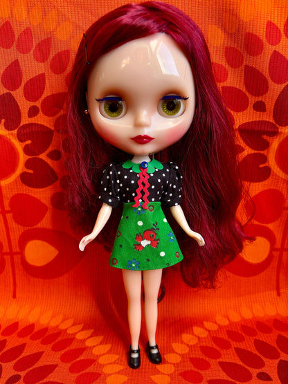 Doll with red hair and a colorful outfit on an orange patterned background