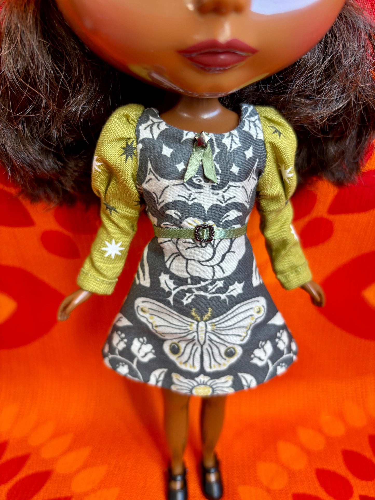 Doll wearing a dress with butterfly design on an orange floral background