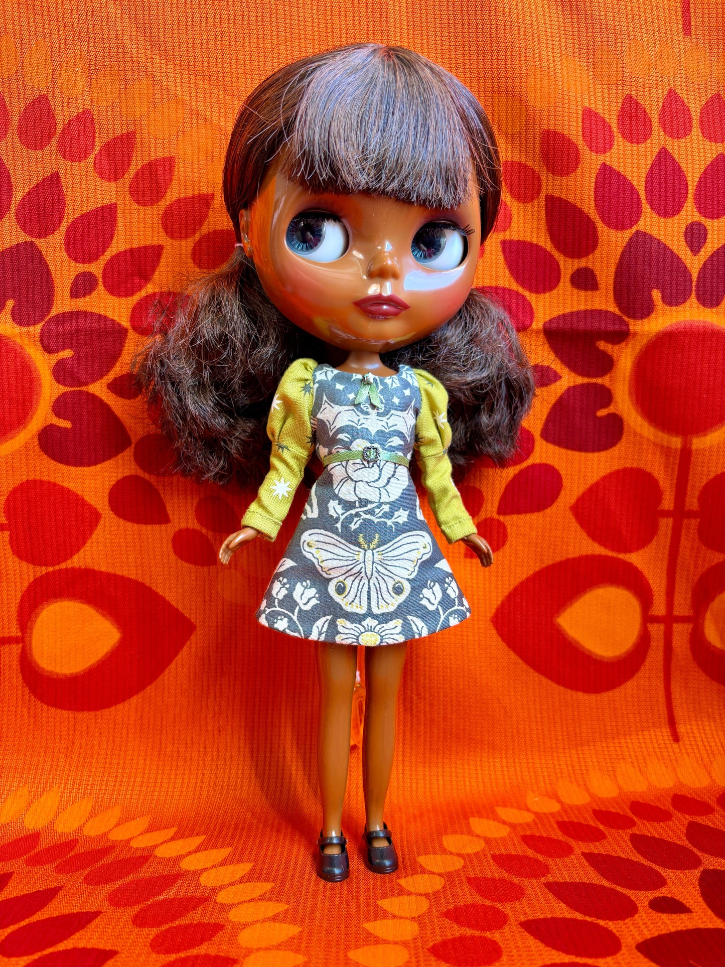 Doll wearing a floral dress on an orange patterned background
