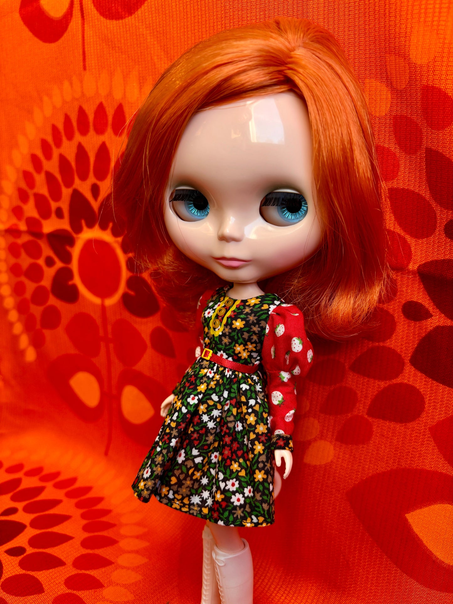Doll with red hair and floral dress against an orange floral background