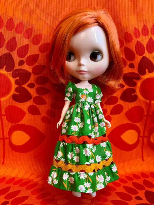  Doll with a green floral dress against an orange patterned background