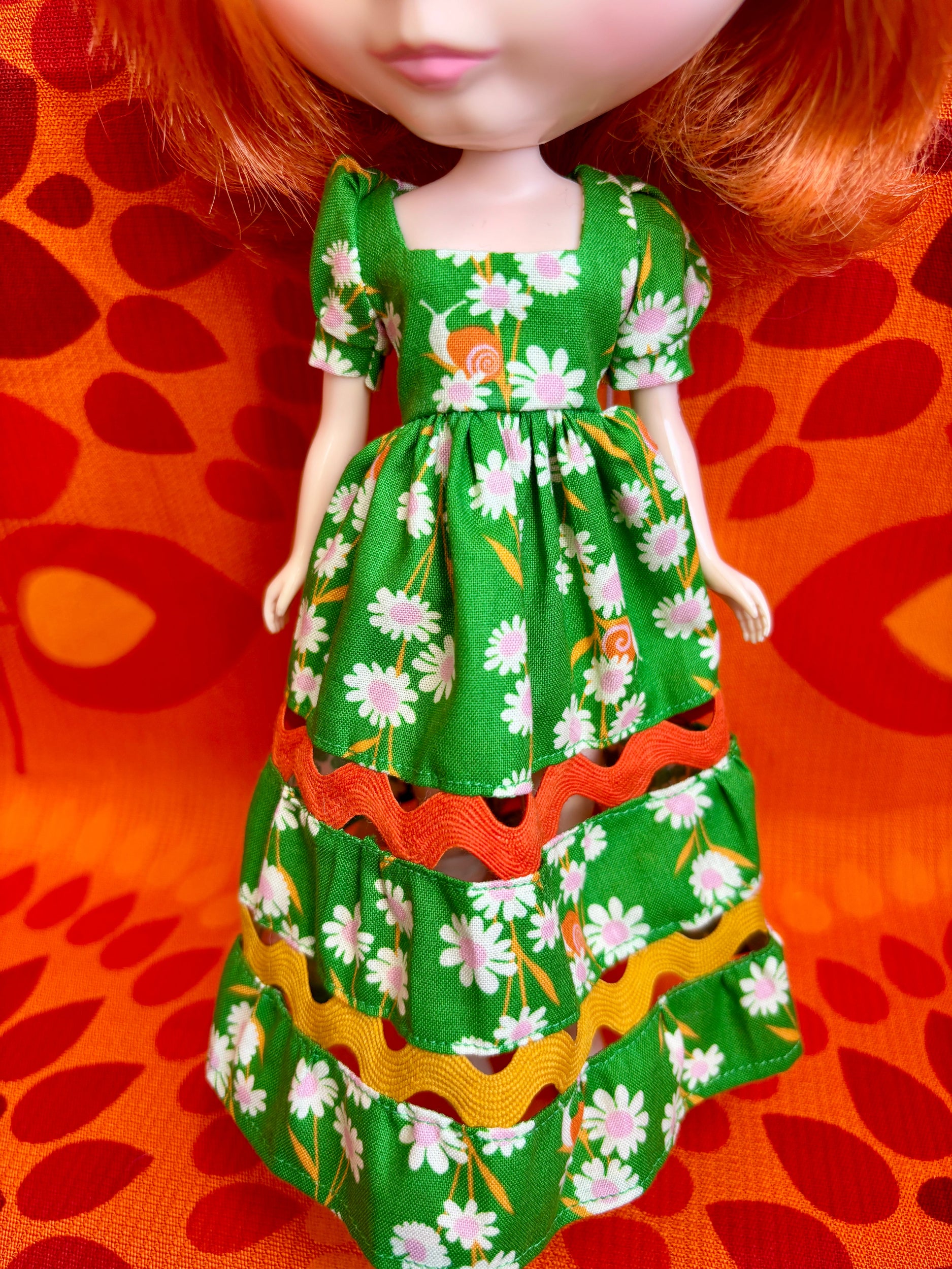 Doll wearing a green floral dress on an orange background