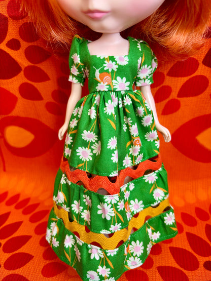 Doll wearing a green floral dress on an orange background
