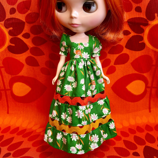 Doll wearing a green floral dress on an orange background