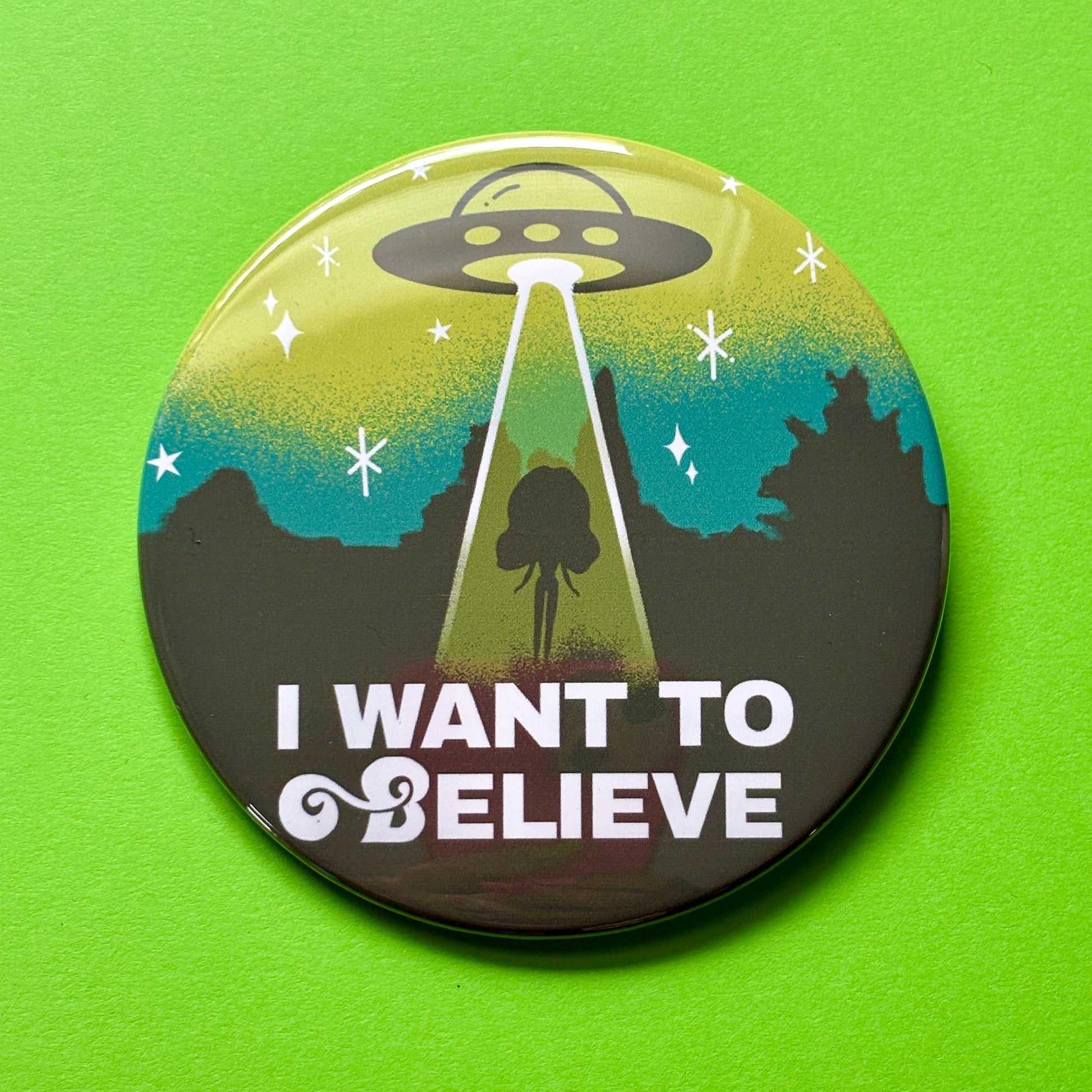 Button badge with UFO design and 'I Want to Believe' text on a green background