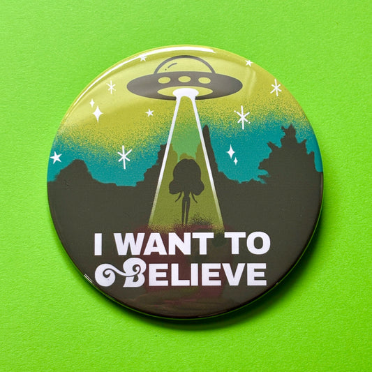 Button badge with UFO design and 'I Want to Believe' text on a green background